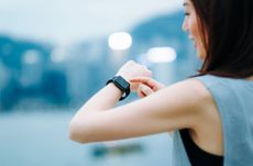 Confident businesswoman checking financial trading data with smart watch in city