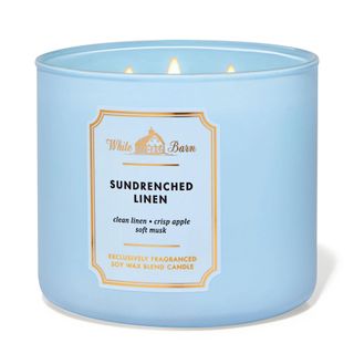 A blue three wick candle with gold detailing