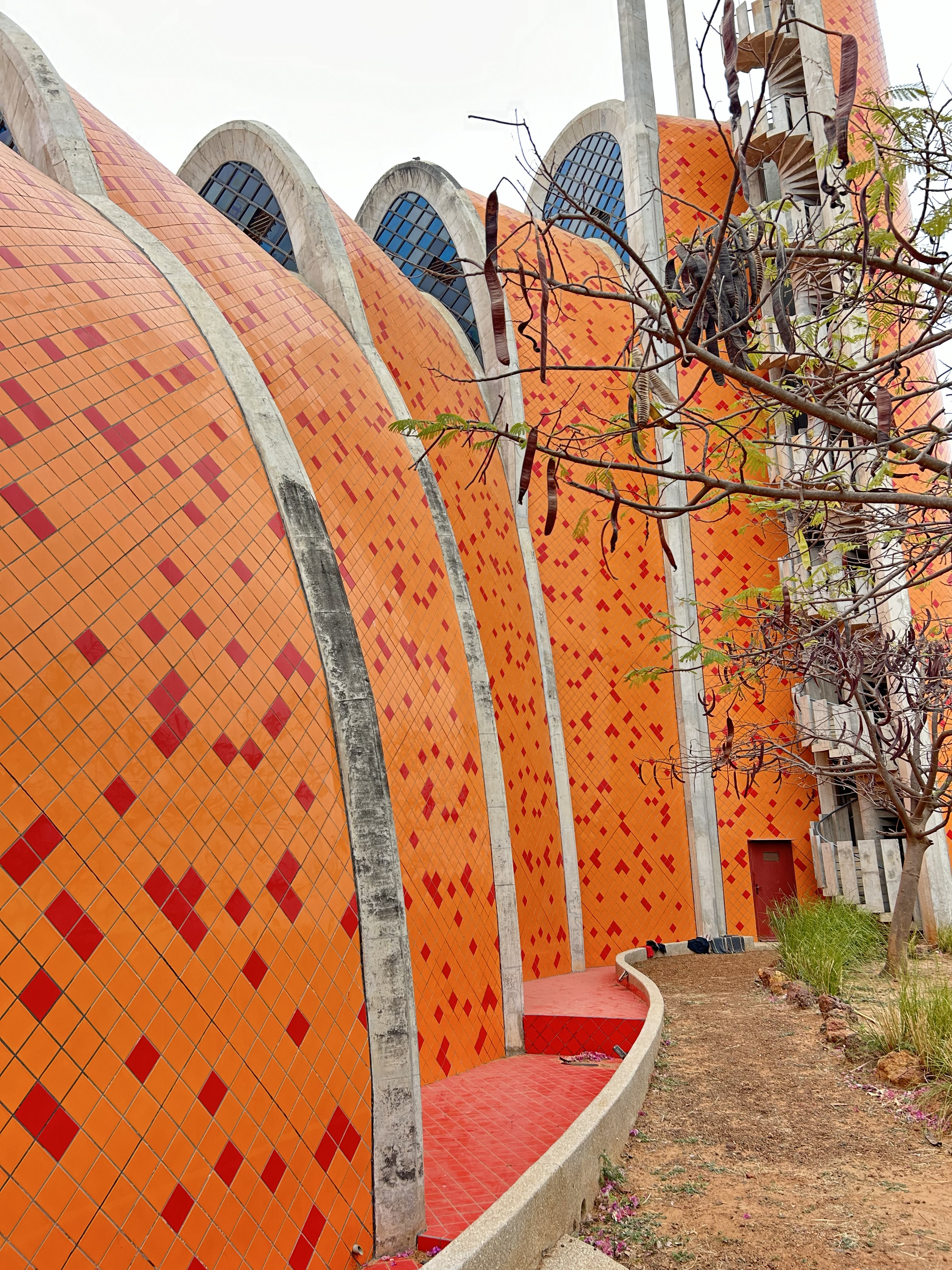 The tiled, orange and red, multi-wave exterior and arched interior of a striking church.