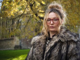 Hasselblad XCD 75P sample image of a woman wearing a fur coat standing in front of trees and a church