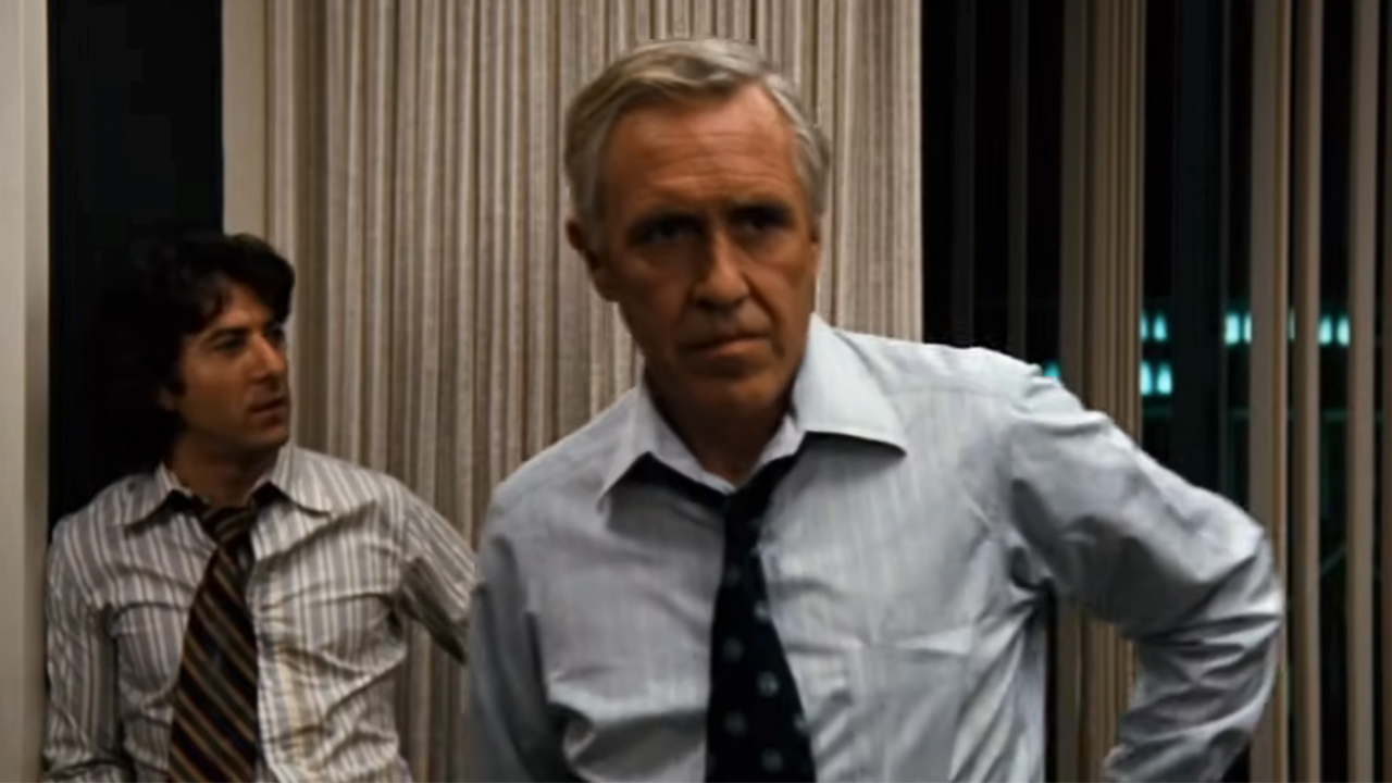 Jason Robards in the foreground looking serious with Dustin Hoffman standing behind him in All the President's Men