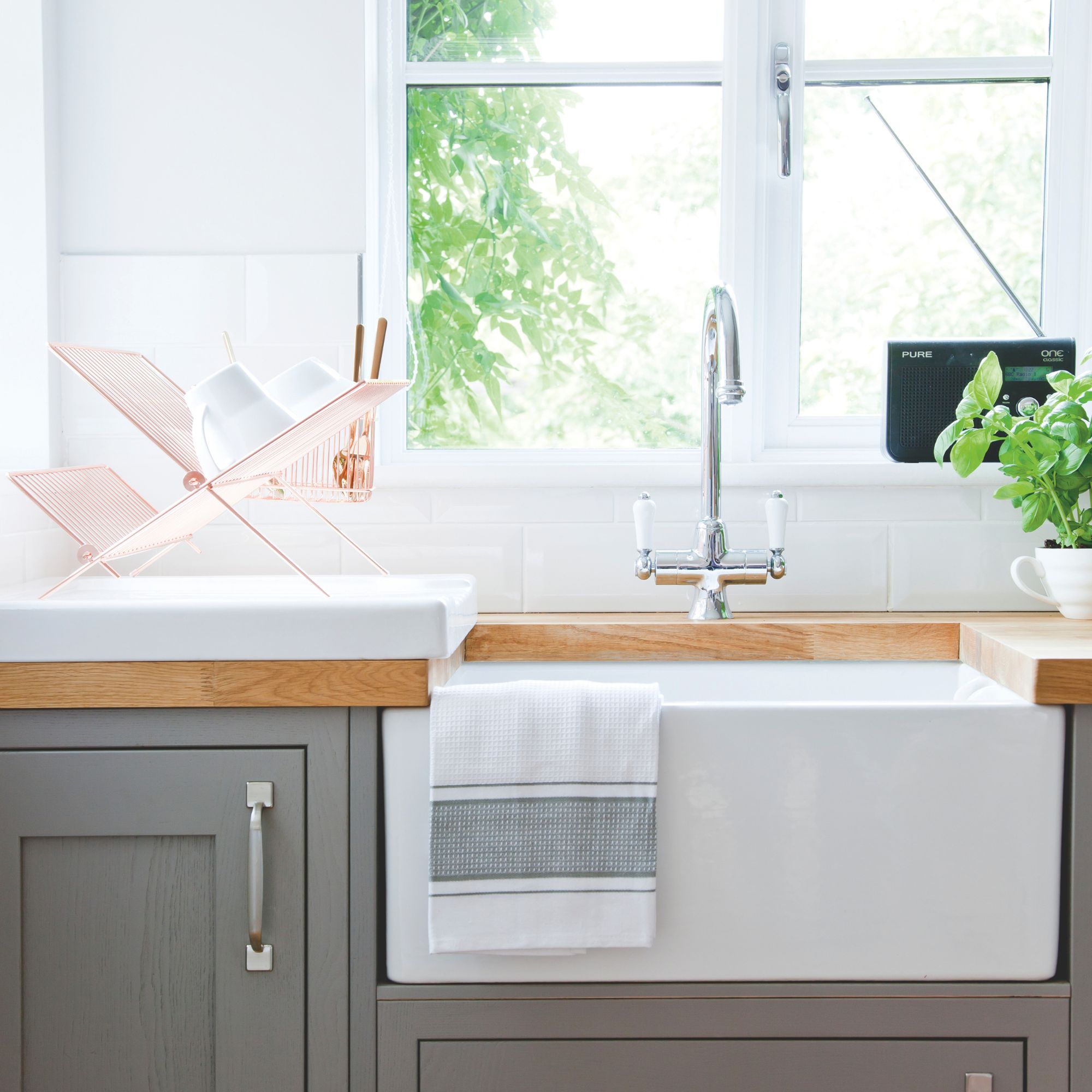 White kitchen with grey kitchen cupboards and a white ceramic sink