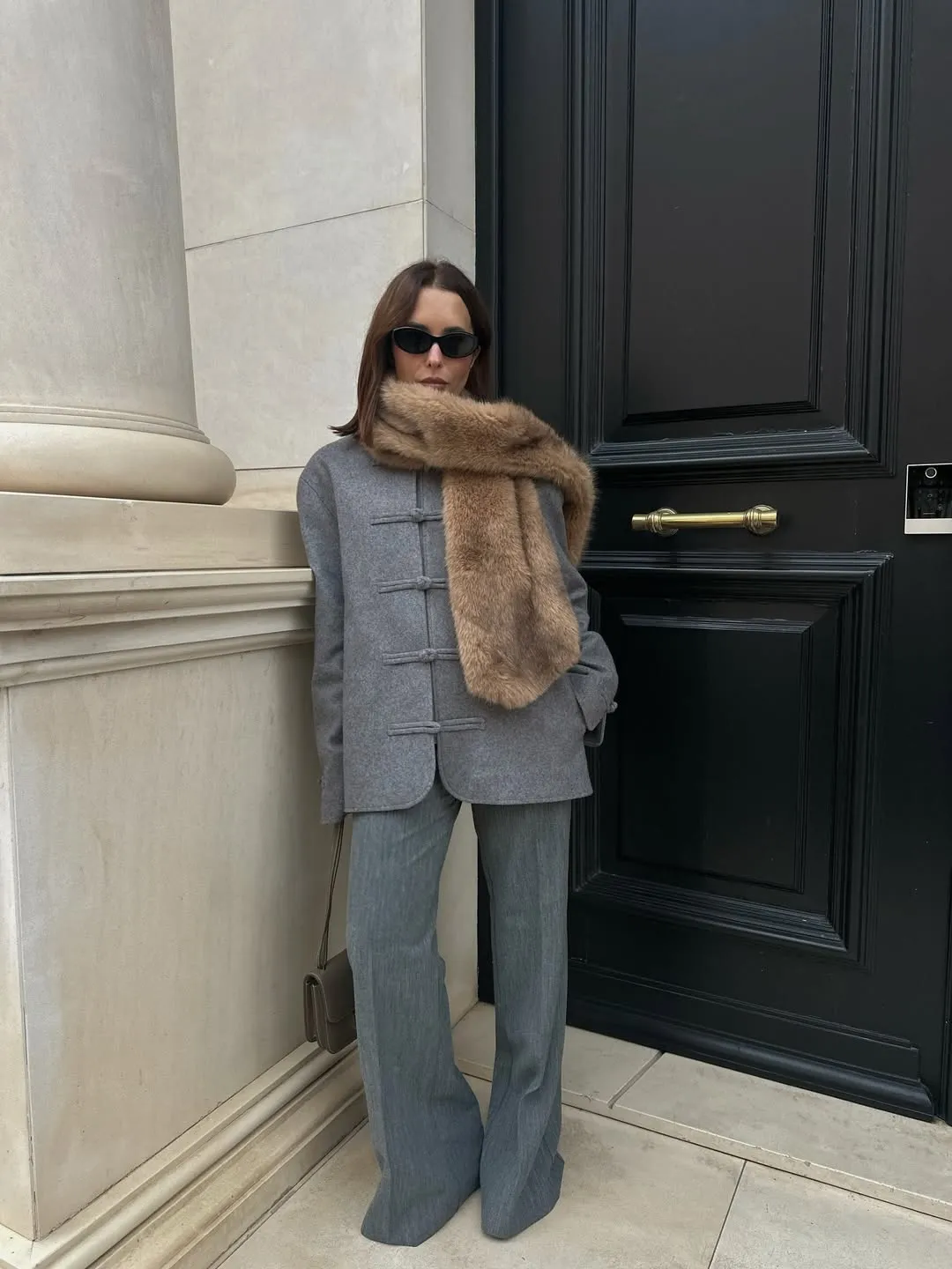 Debora wears a grey frog-fasting knit cardigan jacket with grey trousers