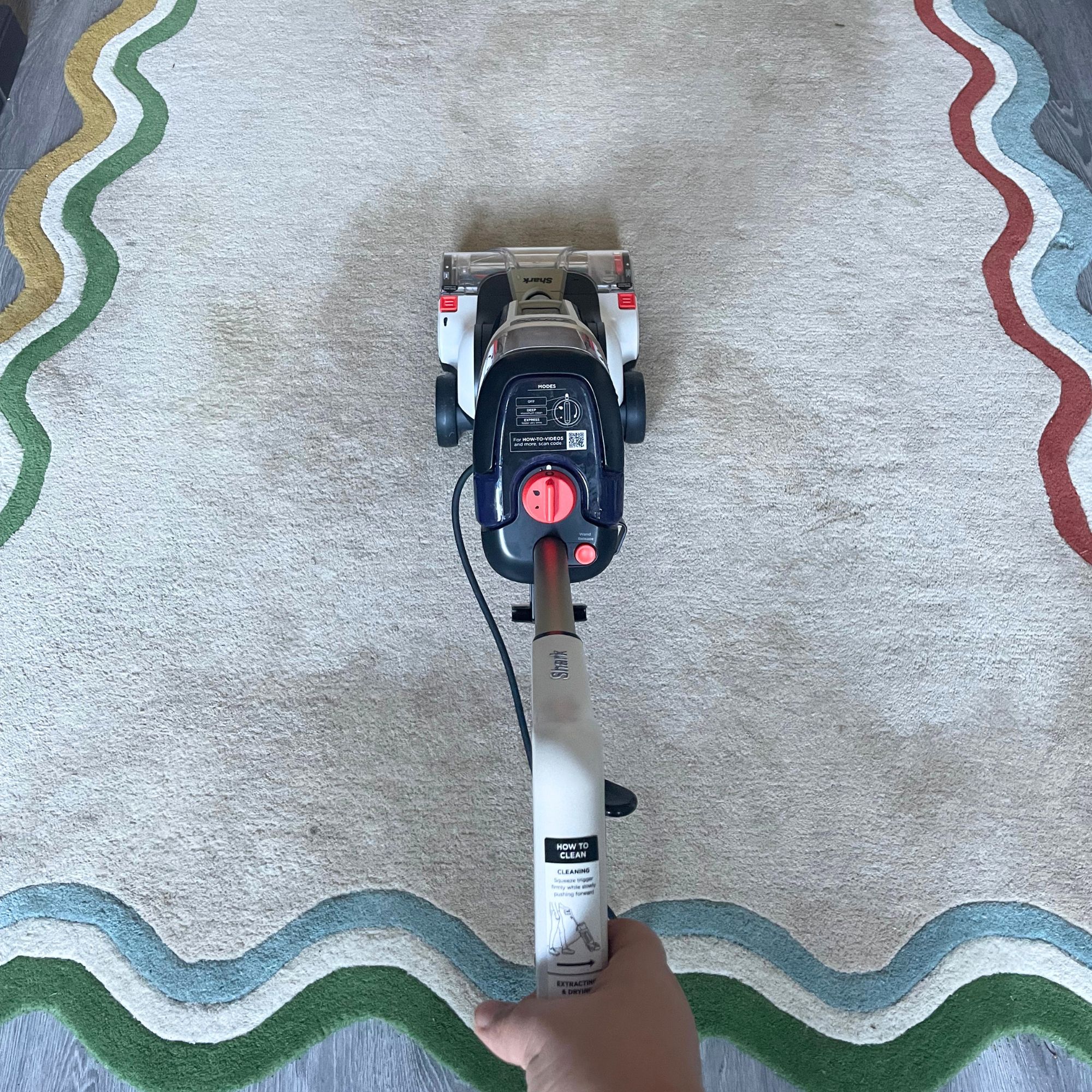 Shark CarpetForce Upright Carpet Cleaner cleaning a cream rug with multi-coloured wiggle edging