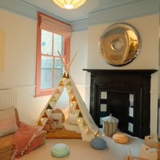 Zac's playroom designed by Tash Bradley with a blue ceiling, an earthy red-painted window frame and a white teepee tent