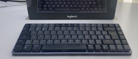 Det trådlösa tangentbordet Logitech MX Mechanical Mini står på ett vitt bord framför sin tillhörande förpackning.
