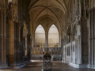 Presbytery with flanking chantry chapels at Winchester Cathedral: The retrochoir. In 1476, St Swithun’s reliquary was moved from the far masonry platform to a shrine set between the chantry chapels of Cardinal Beaufort (left) and Bishop Waynflete (right). Destroyed in 1538, its position is today marked by an iron frame with candles.