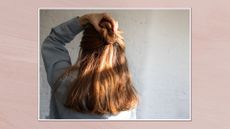 Image showing back view of woman holding her hair in a half up style, in a white frame against a dusky pink watercolour-style background