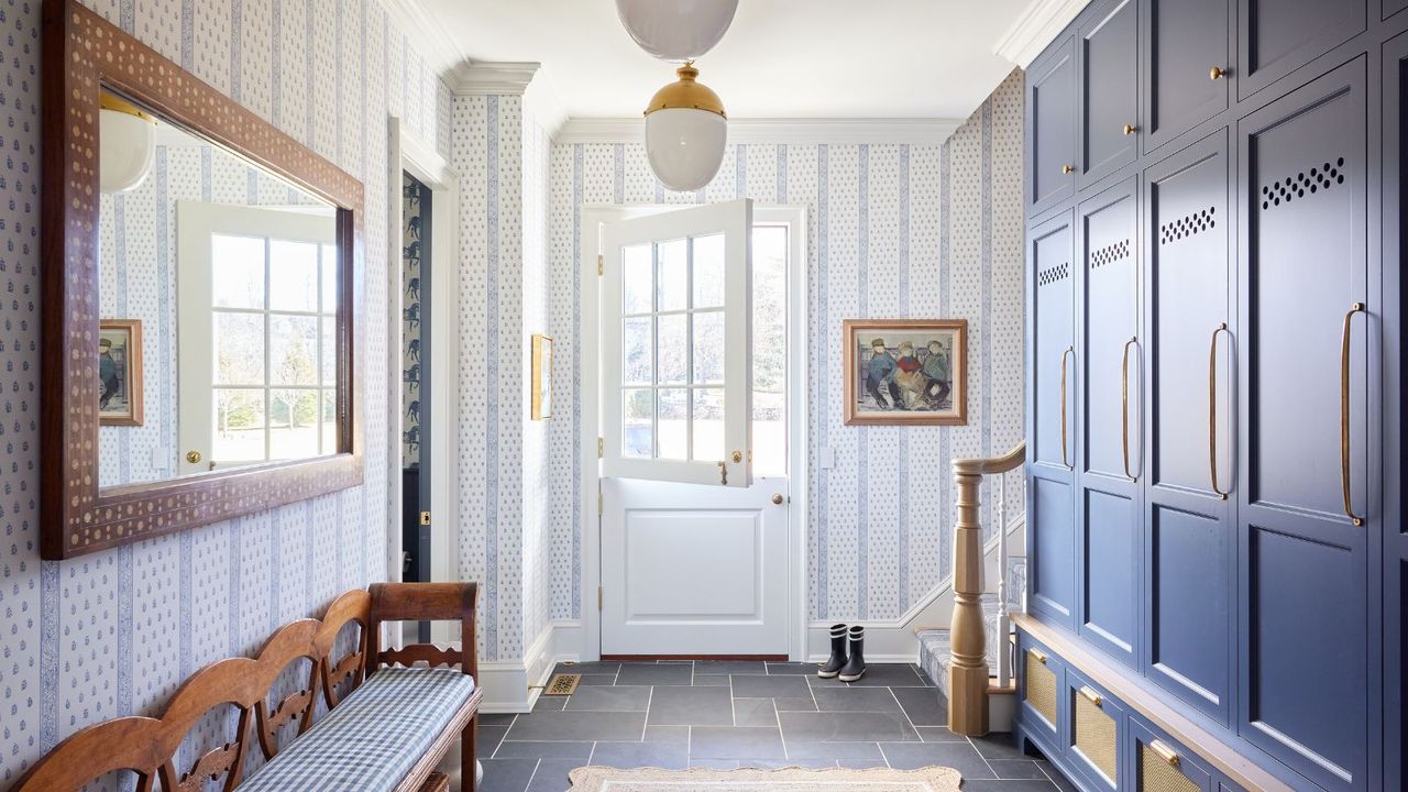 Entryway with dutch doors, glass pendant lights, blue cupboards, wooden bench and large mirror