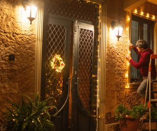 A man hanging Christmas lights on brick