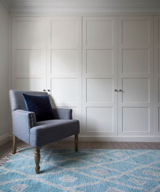 White closets with a blue armchair and blue and white rug