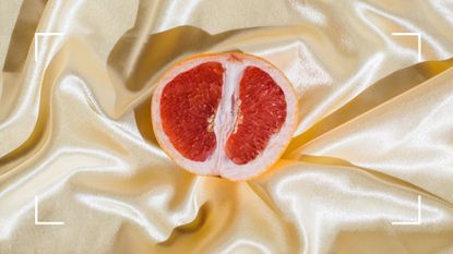 Half a fresh tangerine lying face up on gold satin sheet