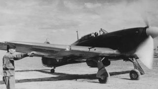 We see a black-and-white wartime photo of a soldier saluting near a Hawker Hurricane plane.