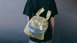 A very expensive yellow carrier bag, worn on a faceless model's back.