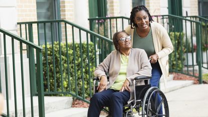 A daughter pushes her mom's wheelchair as they go for a walk.