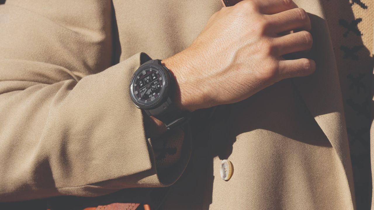 Garmin Instinct Crossover on the wrist of a man wearing a brown coat