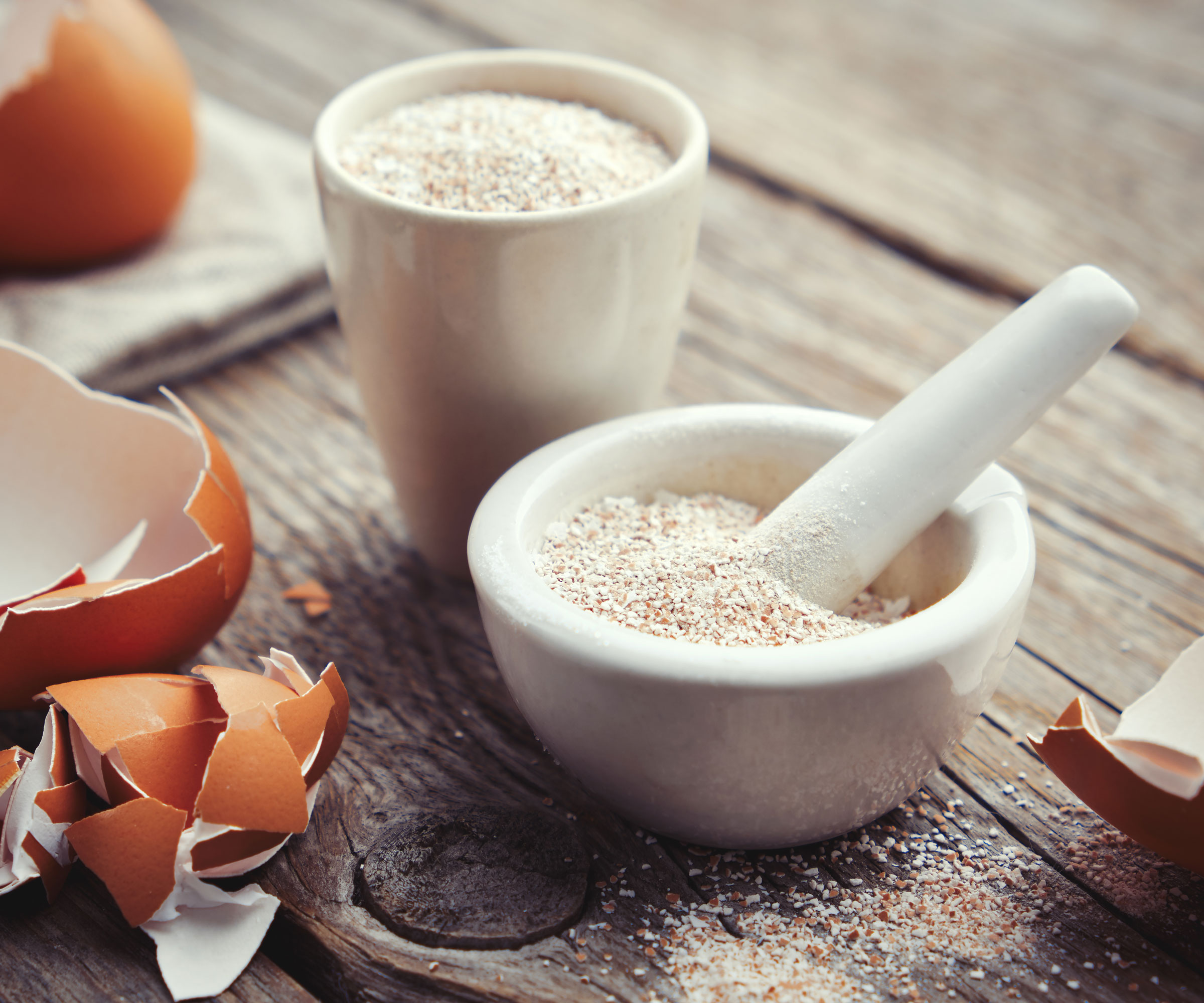 eggshells being crushed with pestle and mortar on wooden table