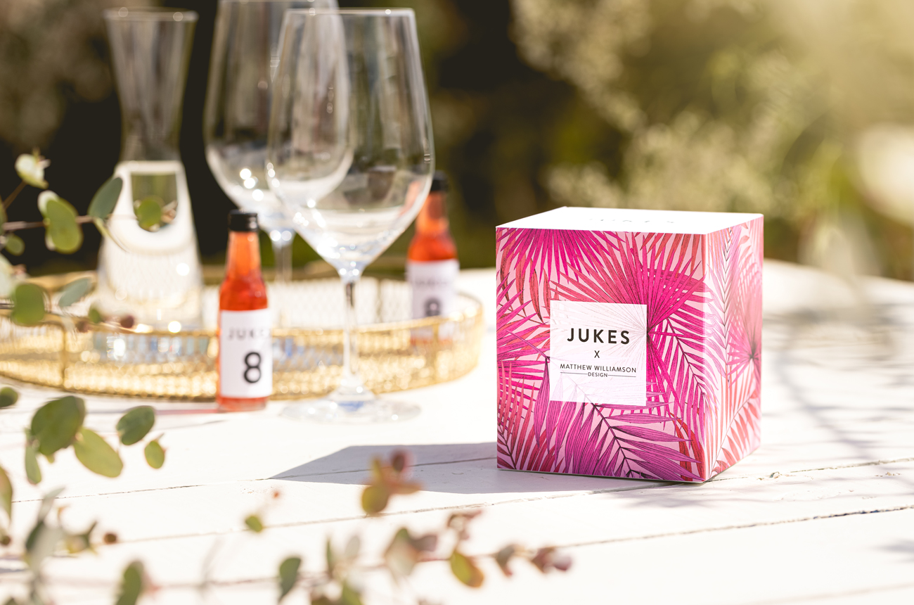 Wine glasses and a box of Jukes Cordials on a summery table