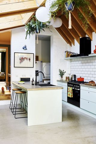 stylish kitchen extension with a glass roof and breakfast bar, in a neutral style with wooden roof beams, and beige countertops and floors