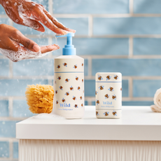 Wild Emma Bridgewater bee deodorant cast and hand lotion, being used by hand with foam. Blue bathroom tiles in background.