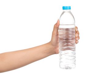 a woman's hand holds up a water bottle