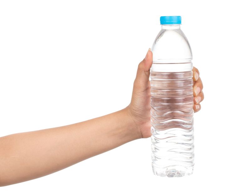 a woman&#039;s hand holds up a water bottle