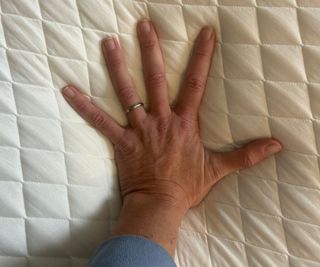 A hand pressing down on the Simba Hybrid Pro Mattress.