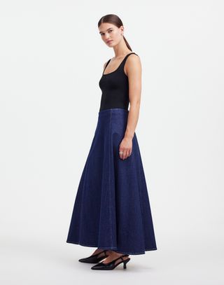 a model wears a denim flare skirt from alexa chung for madewell in front of a plain backdrop