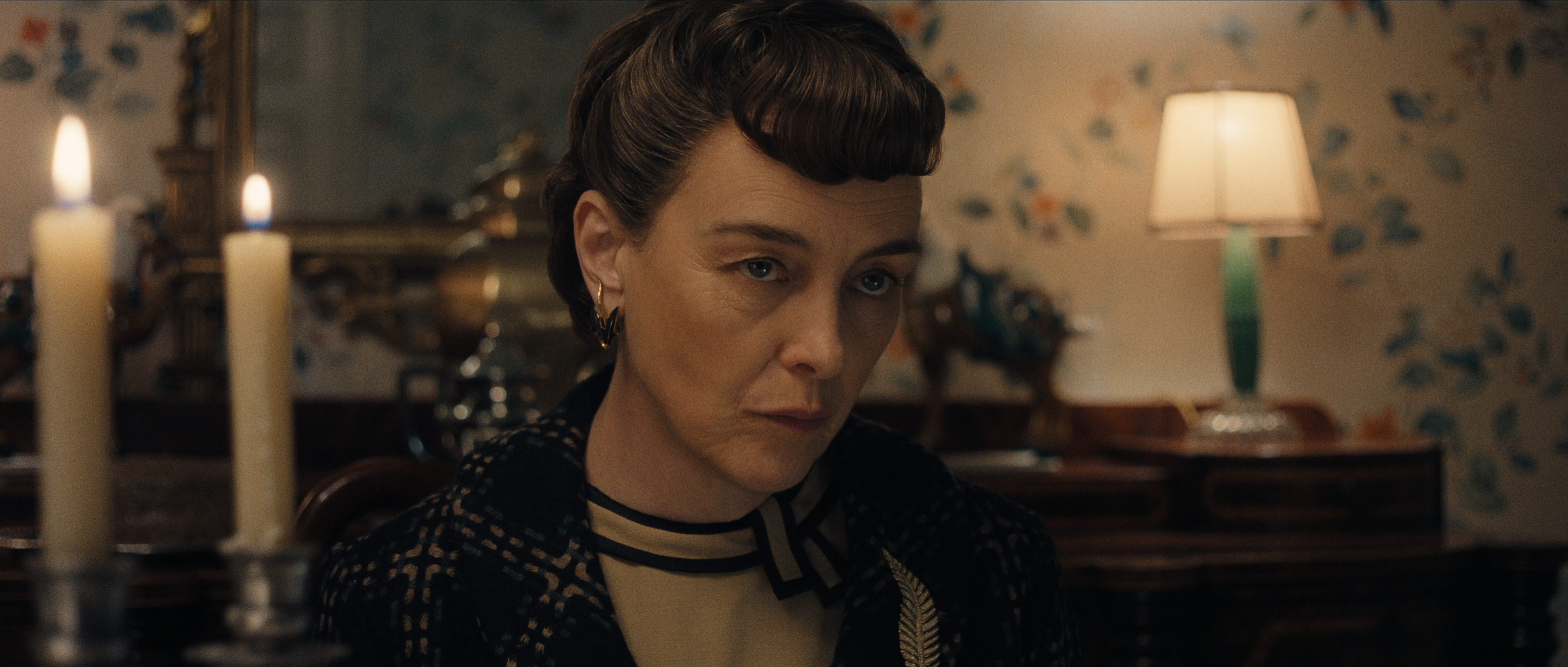 Olivia Williams as alma hitchcock wearing period clothing and looking angry at a dinner table in monster the ed gein story