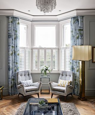 Two armchairs in a bay window with floor lamp living room lighting ideas.