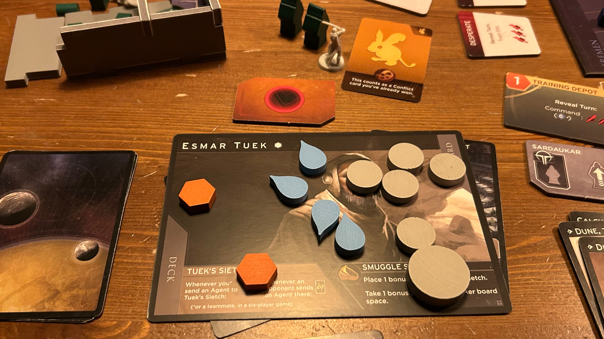A character board with tokens on it from Dune: Imperium - Bloodlines, alongside a variety of other components laid out on a wooden table