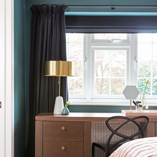 Bedroom in navy with blinds and curtains over wooden desk