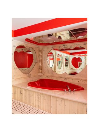 A kitschy hotel room featured red, heart-shaped bathtubs and matching mirrors, evoking a surreal atmosphere.