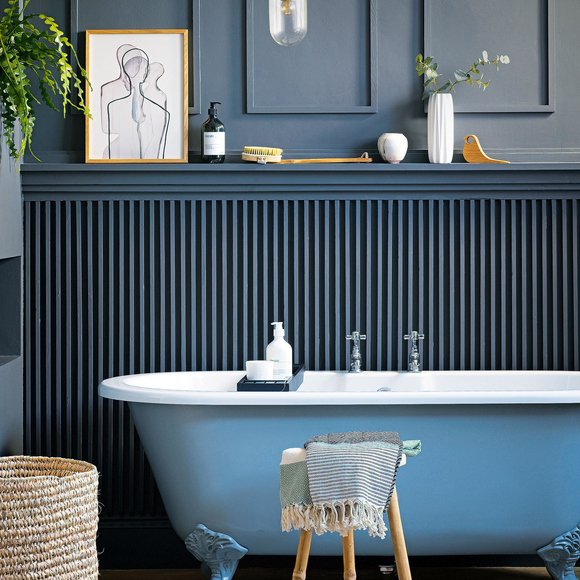 Navy blue bathroom with white bathtub, wooden stool and fluted wall.