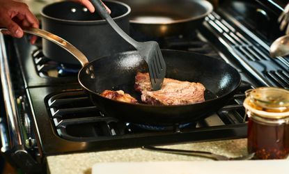 Steak being cooked in a pan on the hob