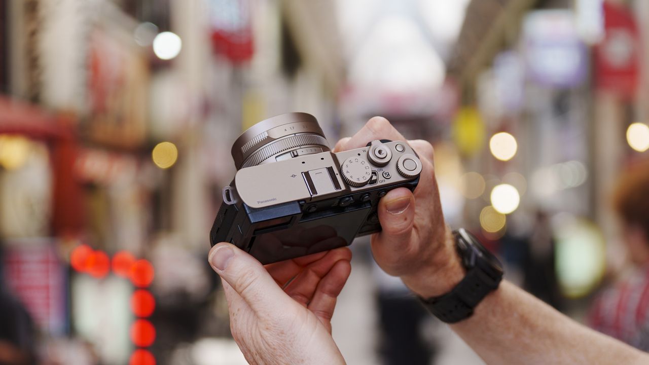 Man holding the Panasonic Lumix L10 compact camera in an urban setting of Japan