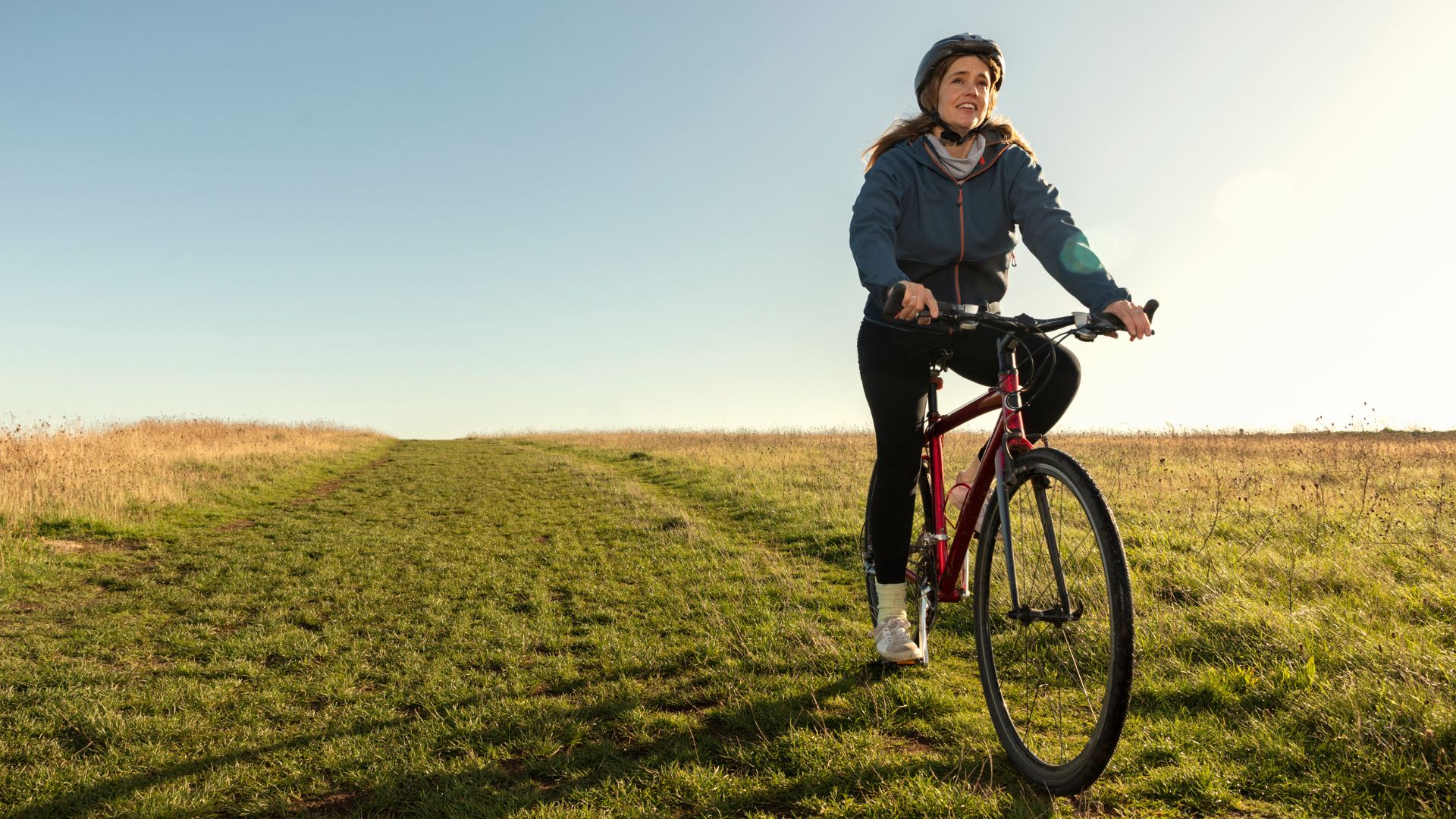 Woman doing cycling as a workout on bike outdoors on grass