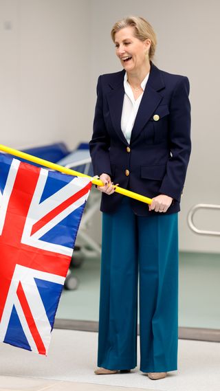 Sophie, Duchess of Edinburgh smiles and waves a Union Jack flag to start a race during a visit to Treloar's School and College