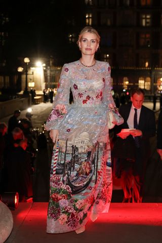 Kitty Spencer wearing a blue lace gown with an embroidered Venetian scene on it, standing on a red carpet outside at night