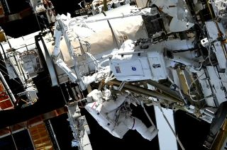 Astronauts Koichi Wakata of the Japan Aerospace Exploration Agency (at left) and Nicole Mann of NASA are seen near the new roll-out solar array mount they partially assembled during a spacewalk outside of the International Space Station on Friday, Jan. 20, 2023.