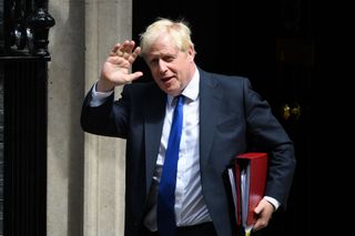 A medium shot of a waving Boris Johnson leaving 10 Downinhg Street