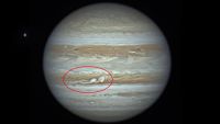 A photo of Jupiter with two white storms (circled) in one of the planet's large brown bands