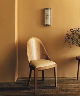Yellow wall with wooden chair in the foreground