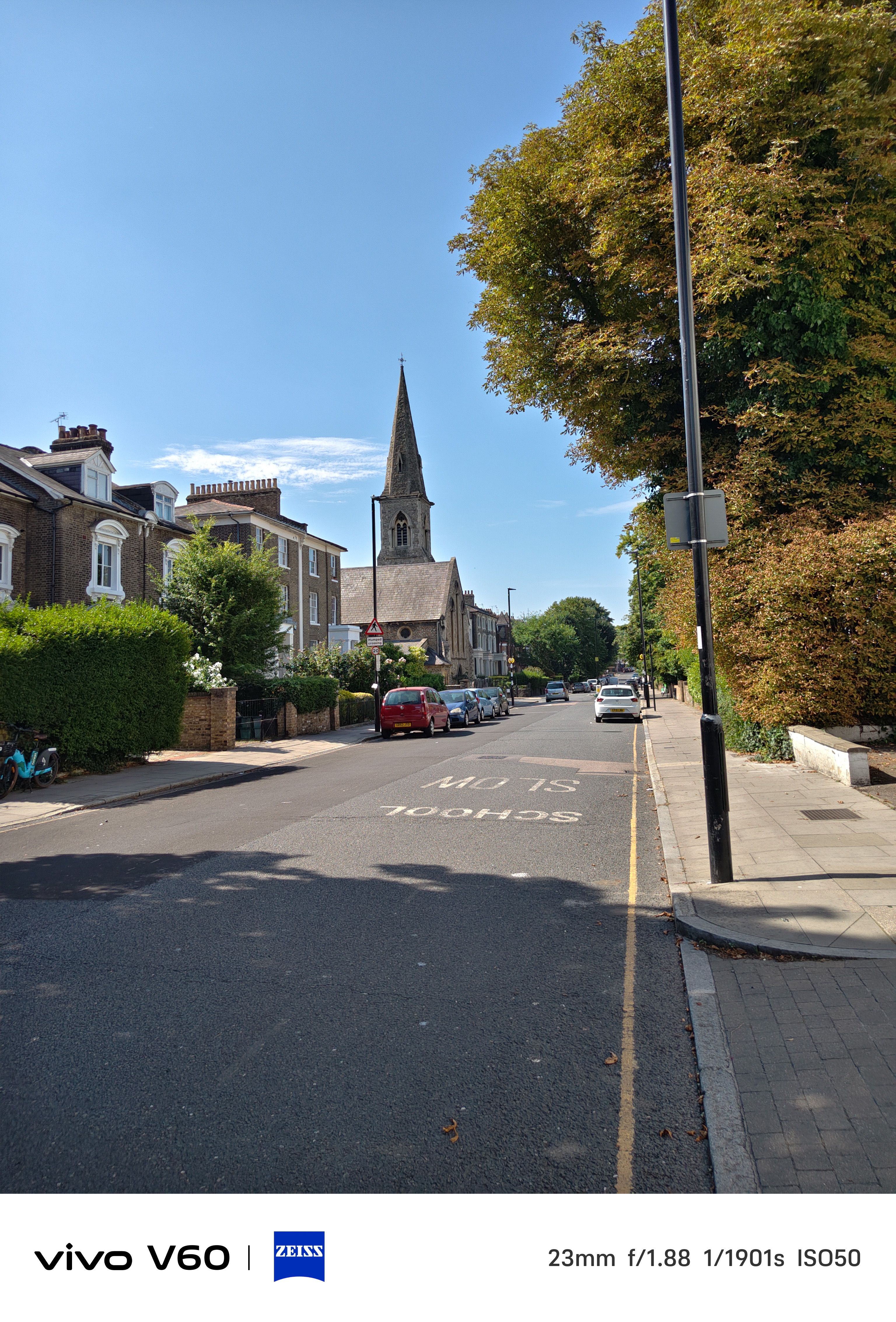 A street in London with a church spire in front of a blue sky