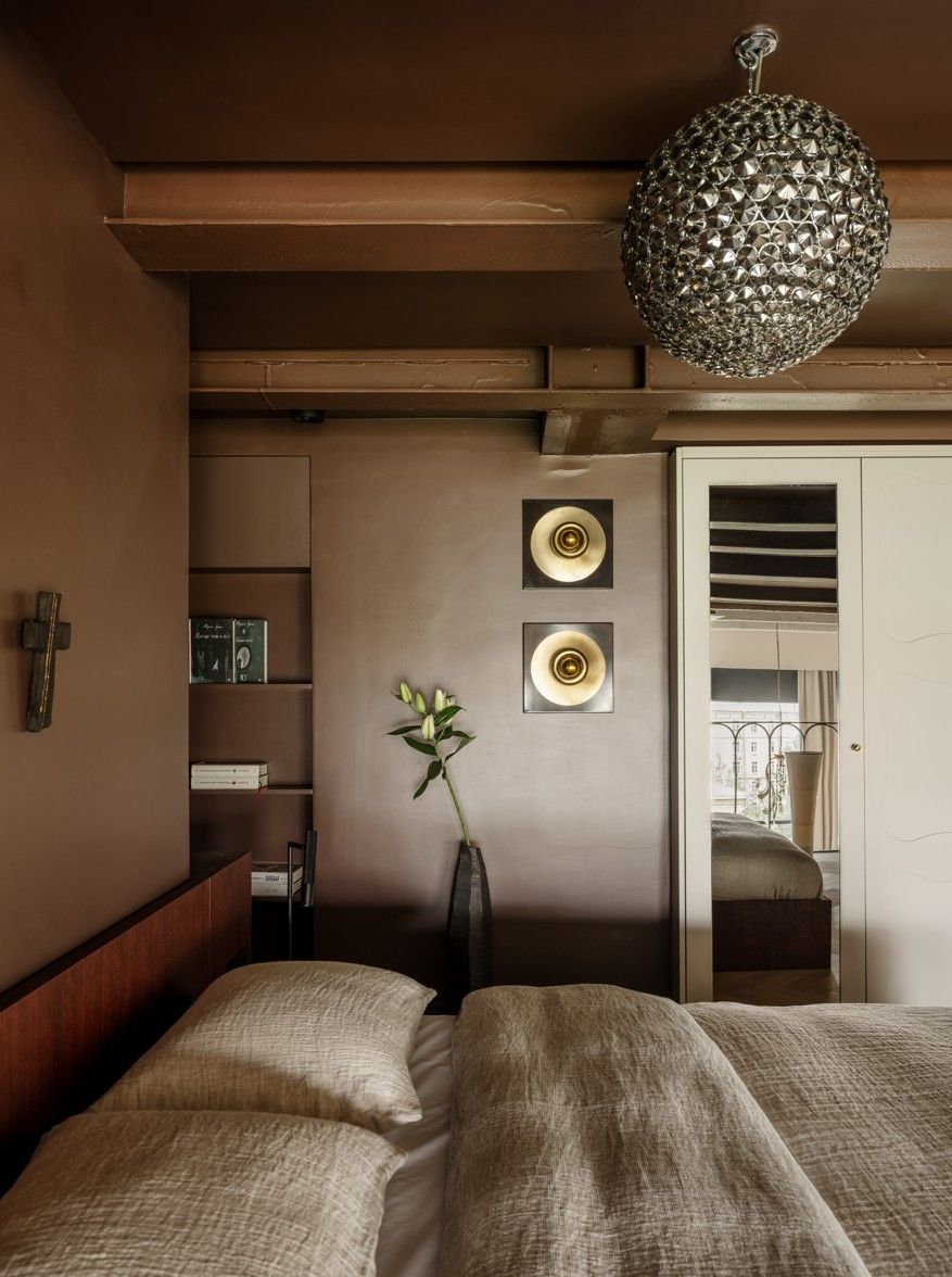 A bedroom with dark brown walls and a metallic chandelier 