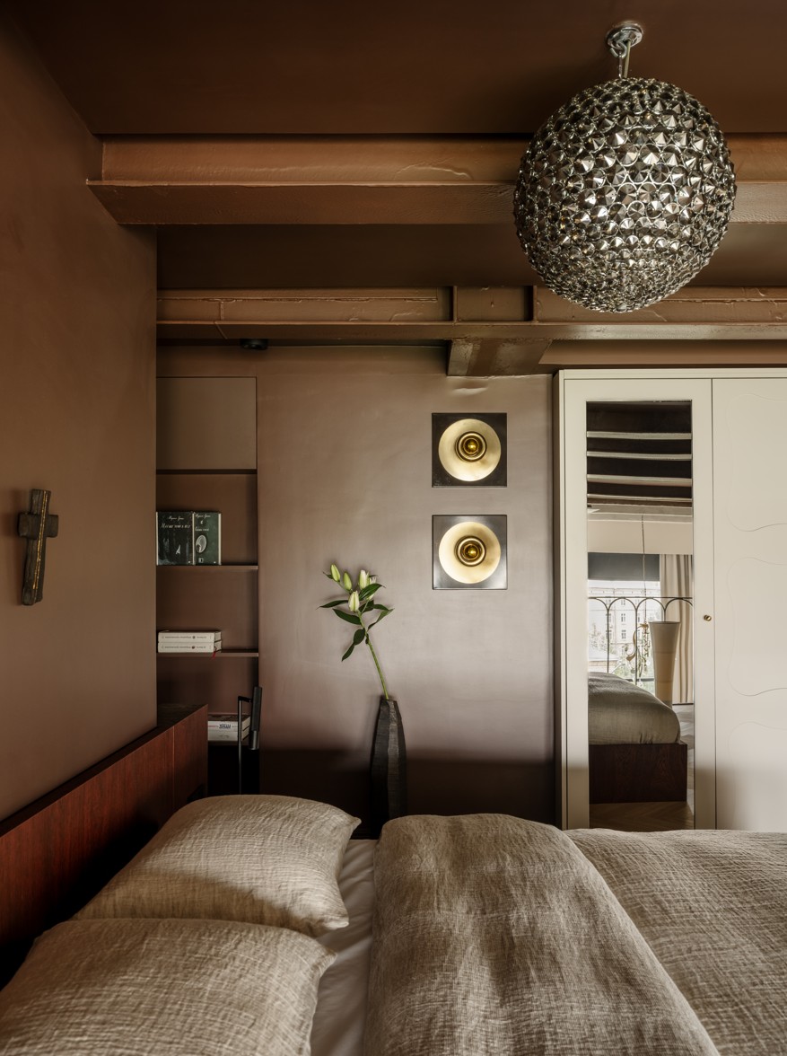 A bedroom with dark brown walls and a metallic chandelier 
