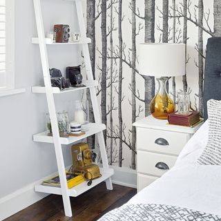 bedroom with white tree designed wall white lamp and white ladder shelf