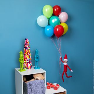 Elf on the shelf floating holding balloons in blue bedroom