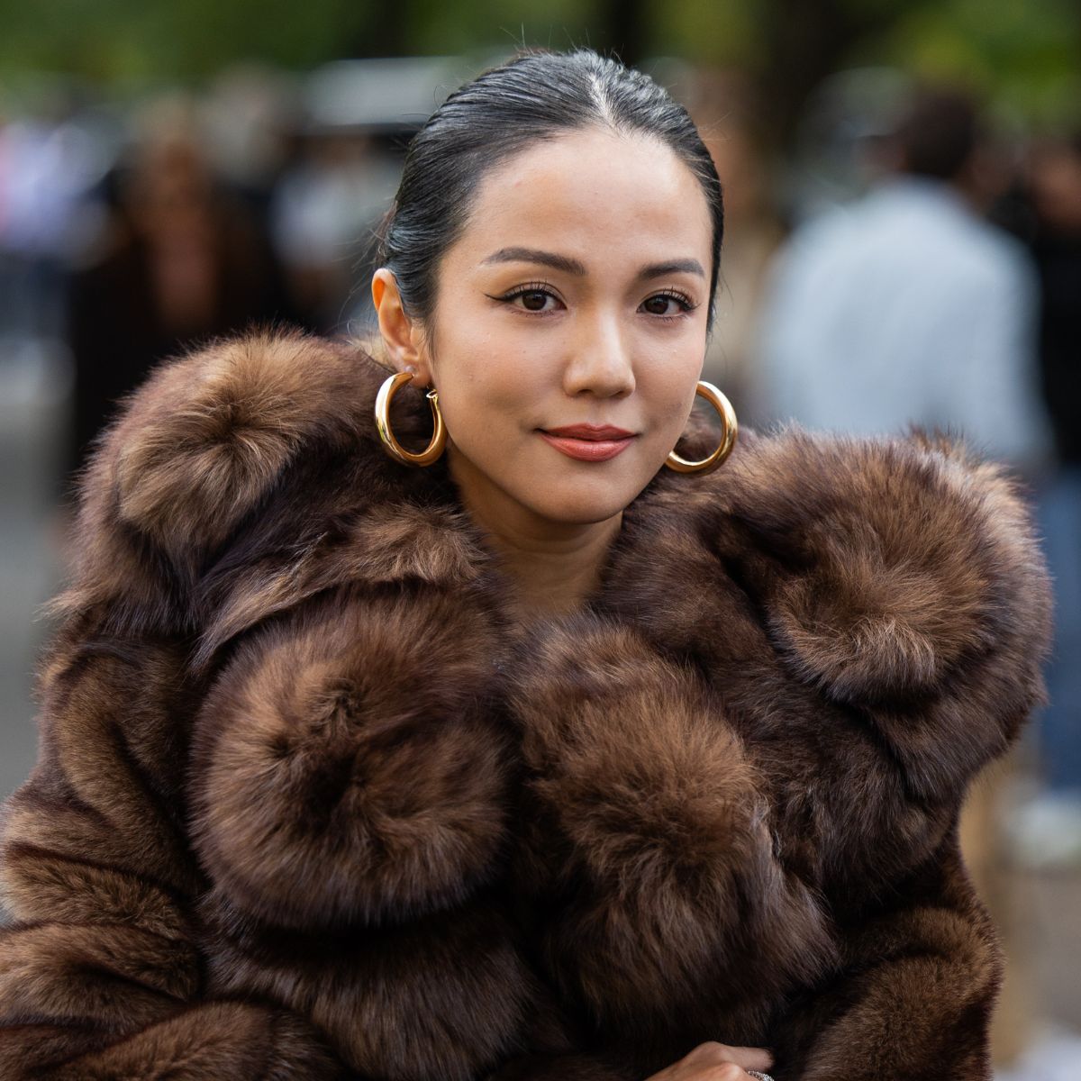 street style shot of woman wearing brown fur coat and gold hoop earrings