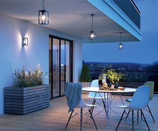 Outdoor lighting on a decked patio area with outdoor dining table and wooden planter